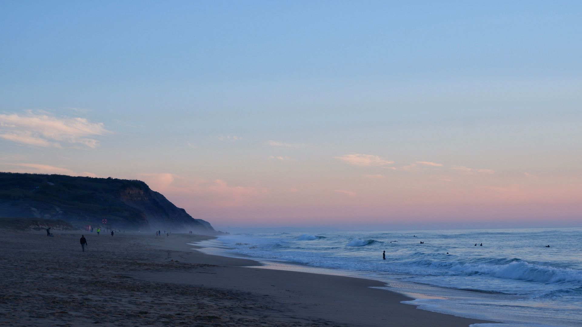A tranquil beach scene at twilight with gentle waves lapping at the shore, evoking calmness and peace.